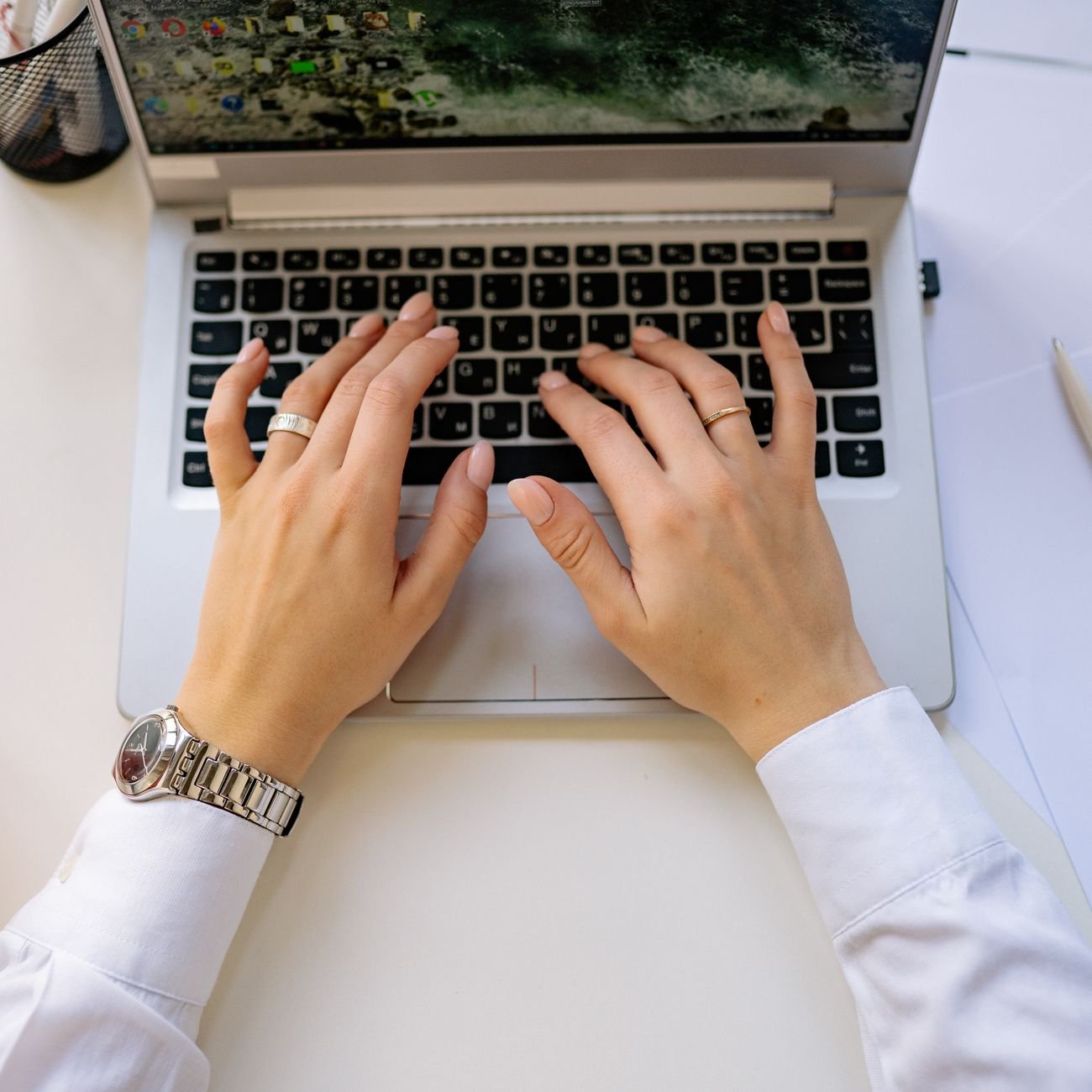 Hands typing on laptop in modern workspace